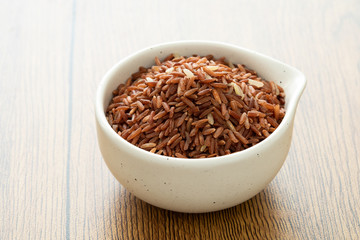 brown rice for healthy white bowl on wood background