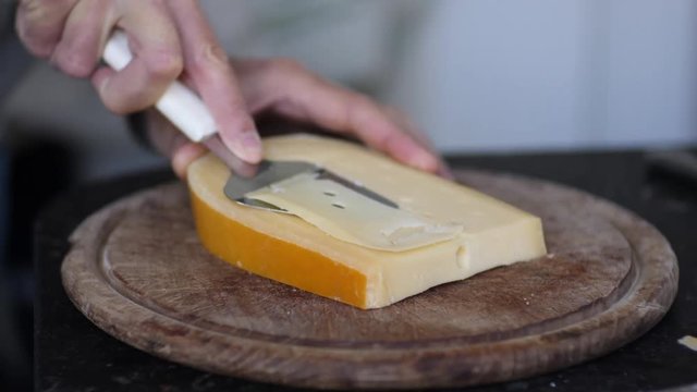 Slicing yellow hard cheese.