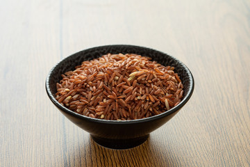 brown rice for healthy black bowl on wood background