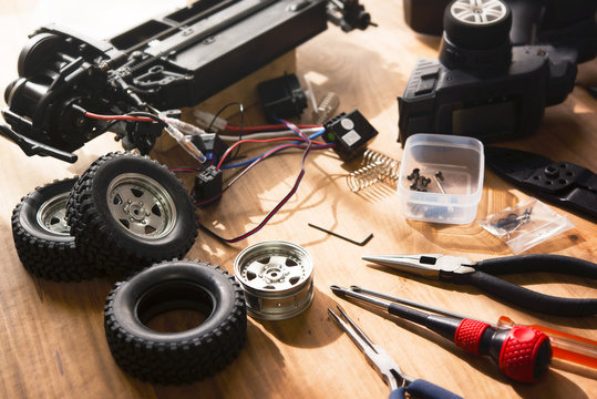 Building Model Cars. Radio Control Car Assembly Scene, RC Car Assembly On Wooden Work Desk And Tools. Natural Lighting.