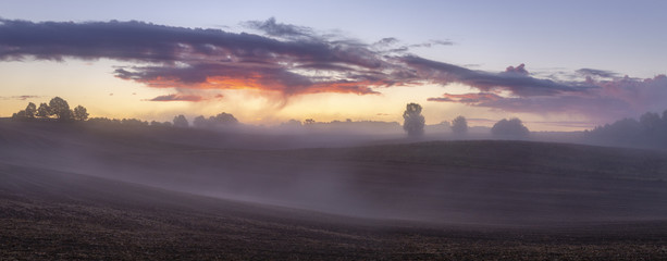 beautiful, dramatic sky over an autumn field enveloped in the morning mists-Poland, Drawskie Lakeland