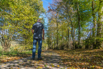 Fototapeta premium Einsamer Mann auf einem Feldweg im Herbst