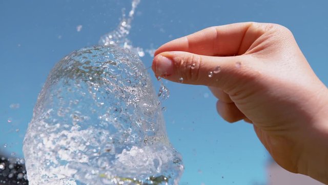 Slow motion, macro yellow water bomb is pierced by a sharp needle held by unknown person