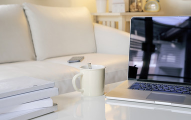 Laptop with blank screen on white coffee table with copy space