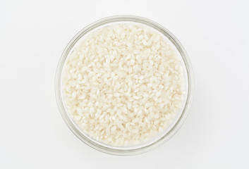 Arroz redondo en un bol de cristal sobre fondo blanco