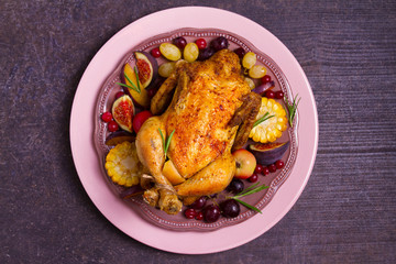 Chicken with fruits, vegetables and berries: apples, figs, grapes, plums and cranberries. View from above, top studio shot