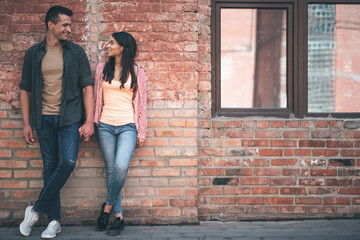 Casual style. Pretty relaxed young man kindly looking at the smiling long haired girlfriend while...