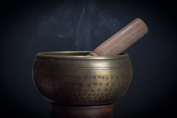 Singing bowl on black background with smoke