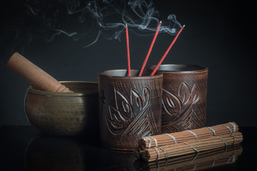 Still-life with steaming incense and beautiful bowls on a black background
