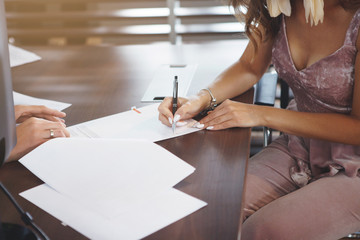 Young woman signs documents in the office.