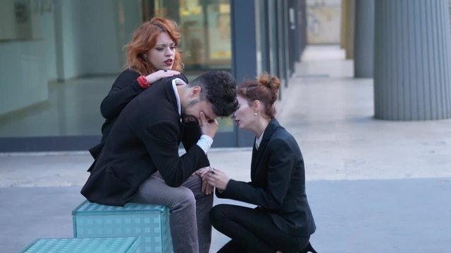 portrait of dismissal, bankruptcy. Two young business women comfort their fired colleague
