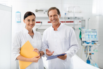 Waist up portrait of smiling health workers on blurred background. Lovely woman holding medical...