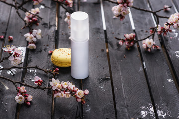 SPA composition. Blank white cosmetic bottle on spring flowers background.