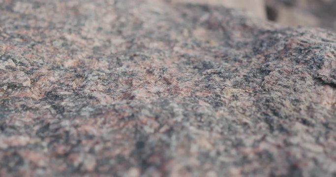 Handheld closeup slide over big granite rock