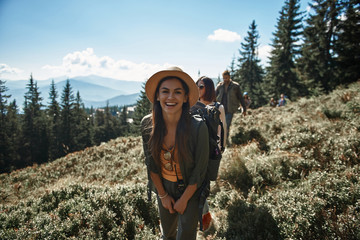 Cheerful attractive young woman enjoying walk on the mountain hills while spending active time together