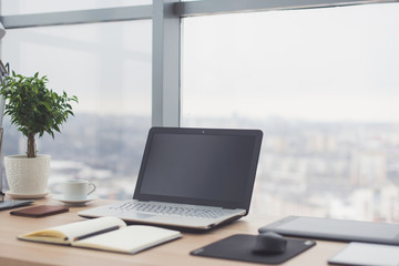 Workplace with notebook laptop Comfortable work table in office windows and city view.