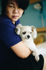 Asian woman hugging dog so cute on bed in bedroom