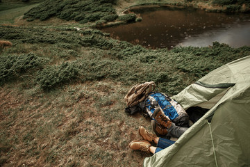 Sleep in tent. Laconic photo of two pairs of feet stretching out of the tent while two tired travelers sleeping in it