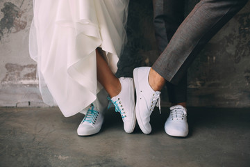 Hipster couple standing together wearing white sneakers. Wedding in sneakers, love. Soft focus...