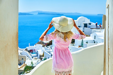 The girl in a pink dress on the background of white houses and the sea