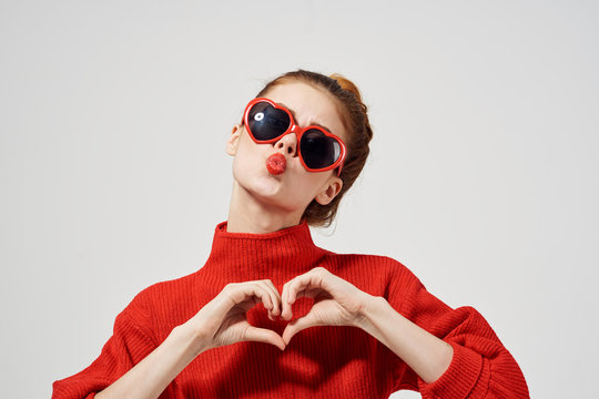 woman in glasses shows heart with her hands