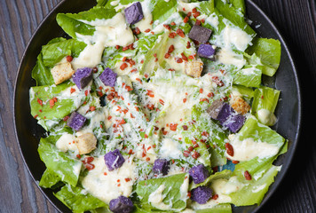 Top view of fresh healthy caesar salad on wooden table