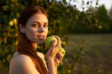 beautiful woman with a green apple in her hand on nature