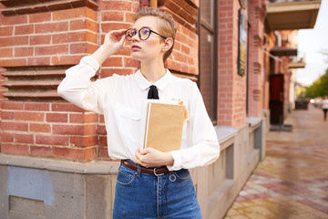 beautiful woman with a book in hand near the brick building
