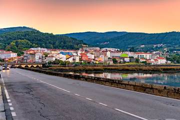 Fototapeta na wymiar Sunset view of Spanish highway and the colorful seaside village of Noia.