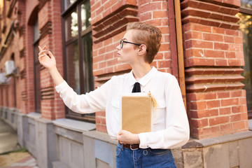 woman stands near a brick building