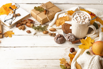 Autumn composition. Dark scarf, a cup of cocoa with marshmallows, autumn dry leaves on a white...