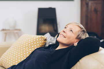 Mature smiling woman relaxing on sofa at home