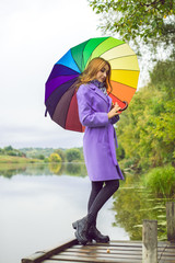 Attractive young casual girl walking in the park with umbrella, autumn day. Weather and people concept - nice lady with umbrella on nature. England rain  