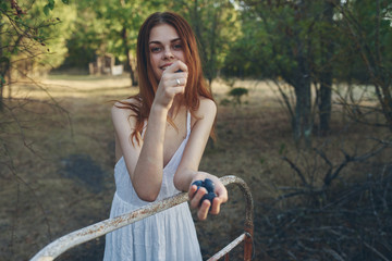 beautiful woman with grapes in her hand stands near the iron railing on nature