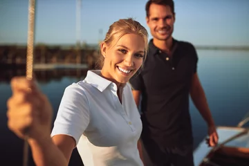Stoff pro Meter Smiling young couple standing on the deck of their yacht © Flamingo Images