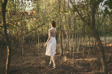 woman in a light dress on the nature in the forest