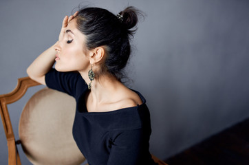 beautiful woman with dark hair sitting leaning on a chair