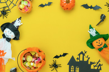 Table top view aerial image of decoration Happy Halloween day background concept.Flat lay accessories essential object to party the pumpkin & sweet candy on yellow paper.Space for creative design.