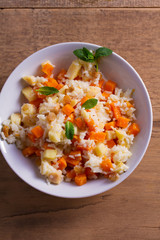 Rice porridge with pumpkin, apples and raisins in white bowl. Vegetarian diet dish of rice and pumpkin. Healthy food. overhead, vertical