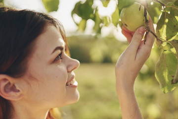 woman looking at a green apple in a tree