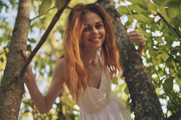 beautiful woman stands near tree trunks