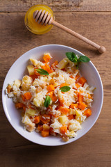 Rice porridge with pumpkin, apples and raisins in white bowl. Vegetarian diet dish of rice and pumpkin. Healthy food. overhead, vertical