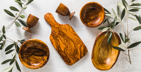 banner of wooden utensils from the olive tree on the white kitchen table and the branches of the olive tree. eco-friendly kitchenware