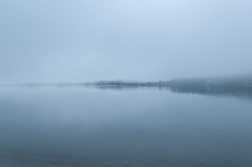 Obraz na płótnie Canvas Foggy morning on the calm lake in Austrian Alps