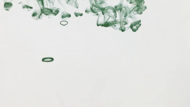 Drops of green ink flowing from top to bottom under water.