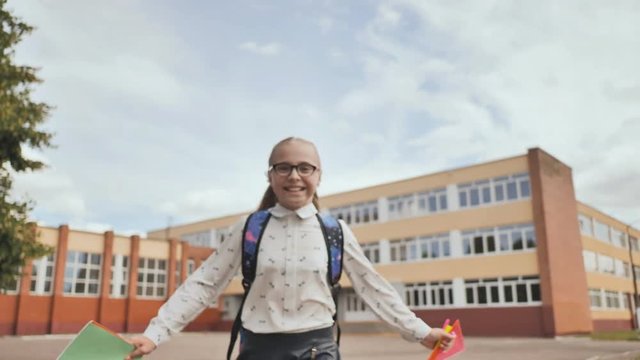 Happy eleven-year schoolgirl runs with a backpack after school.