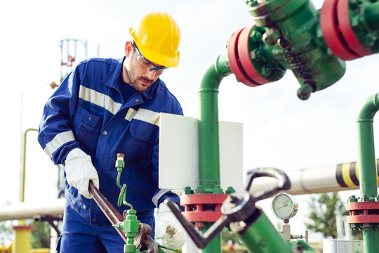 Worker adjusting gauge at oil refinery