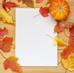 Naklejka na ściany i meble Blank sheet of paper with frame of orange leaves and pumpkin on wooden table. Autumn mood concept. copy space for text