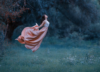 A young woman, a mysterious witch is floating in the air like a butterfly. A luxurious, long dress...
