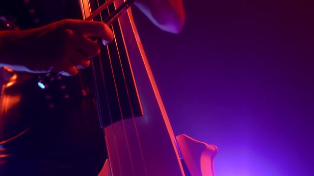 Cellist with electronic cello performs on stage.